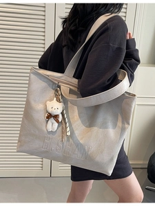 Chic beige lychee leather tote bag with H.SHAN logo and bear charm shown on model