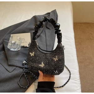 Detail of black tweed crescent bag with silver butterfly charms and chain strap