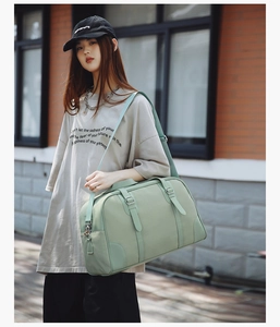 Detail view of light green travel bag showing reinforced handles and silver buckle straps