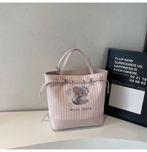 Dettaglio della borsa shopper a righe rosa con orso cartone e manici in pelle