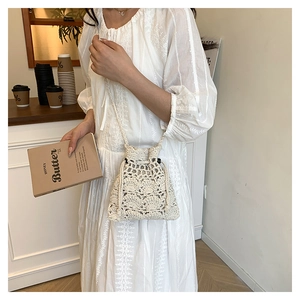 Détail de la texture florale crochetée main sur un sac seau blanc cassé avec cordon