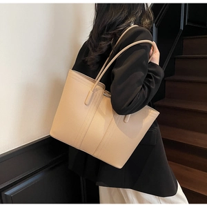 Détail du cuir à grain lychee et coutures renforcées sur un sac cabas beige élégant