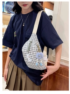 Détail du sac bandoulière pied-de-poule avec écusson STAY et pendentif monstre bleu