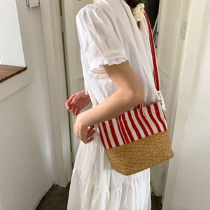 Close-up of canvas stripes and straw base on a beach tote bag with metal buckles