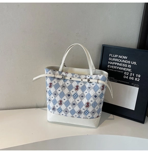 Détail du sac cabas à motif losanges bleus avec imprimé ours et sangle en cuir blanc