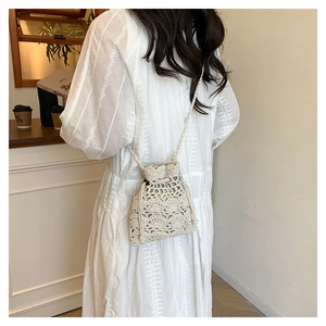 Détail du sac seau au crochet crème avec motifs floraux ajourés et cordon de serrage