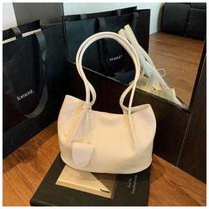 Detail of creamy white lychee grain leather tote with slim straps and side knot accent