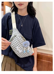 Détail du sac de poitrine pied-de-poule avec patch STAY et charm monstre bleu
