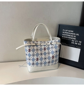 Dettaglio della borsa tote a quadri blu e bianchi con motivi di orsi e fiocchi