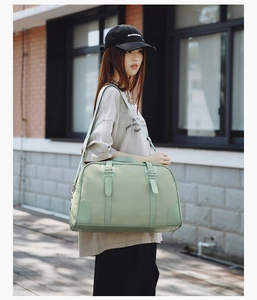 Close-up of a mint green travel bag with textured fabric and adjustable wide strap