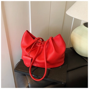 Detail of red lychee pattern bucket bag with drawstring closure on dark surface
