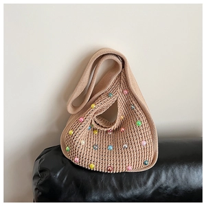 Close-up of beige knitted shoulder bag with colorful iridescent beads on black leather