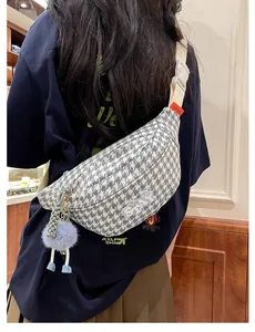 Détail du sac bandoulière pied-de-poule avec broderie STAY et pompon en peluche