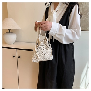 Vue détaillée du sac seau au crochet crème avec motif ajouré et cordon à perles en bois