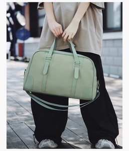 Close-up of light green Boston travel bag with leather texture and adjustable strap