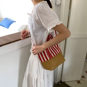 Detail of red and white striped canvas combined with woven straw base on a tote bag