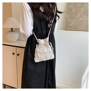 Détail d'un sac seau au crochet beige avec motif ajouré et fermeture à cordon de serrage