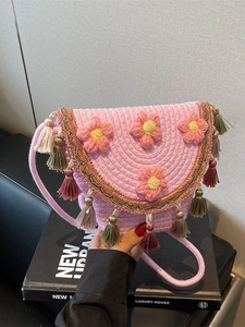 Woven pink straw bucket bag with floral accents and colorful fringe tassels