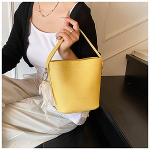Detail of yellow bucket bag with lychee texture and elegant pearl tassel pendant