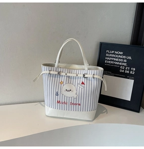 Détail du sac en toile rayé bleu avec imprimé phoque et finition de poignée en cuir blanc