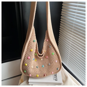 Detail of light beige crochet tote bag with colorful beads on a white book surface