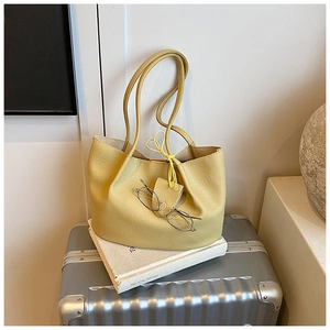 Close-up of mustard yellow pebbled leather tote bag with long straps and metal glasses