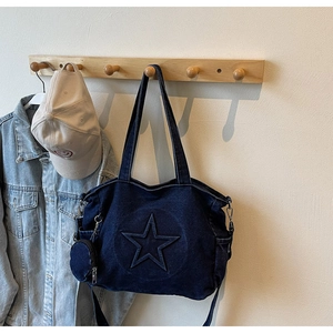 Détail du sac cabas en denim bleu avec surpiqûres étoiles et petite pochette ronde