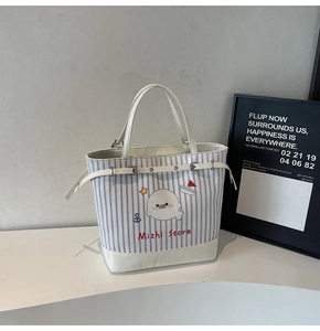 Dettaglio della borsa tote in tela a righe blu con stampe cartoon e manici in ecopelle