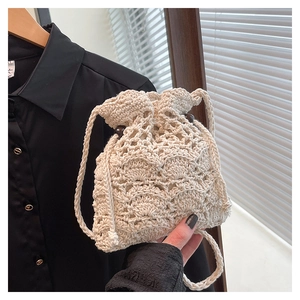 Détail du sac seau au crochet beige ajouré avec fermeture par cordon et perles en bois