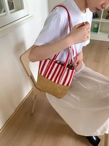 Detailed macro of the canvas stripe stitching and woven straw texture on a tote bag