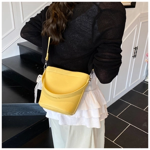 Detail view of yellow bucket bag with lychee texture and pearl lace ornament