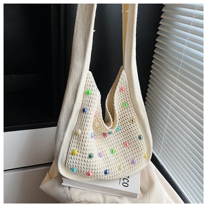 Detail of cream knit tote bag with colorful pearl accents and hollow weave texture