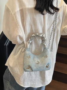 Blue glitter dumpling bag with silver butterfly charms and pleated handle on shoulder