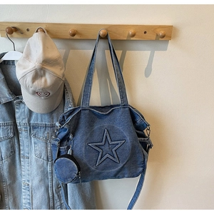 Close-up of a blue denim tote bag with embossed star detail and mini pouch on a hook
