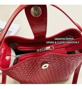 Détail macro du sac seau tressé rouge montrant la fermeture éclair et le fermoir aimanté