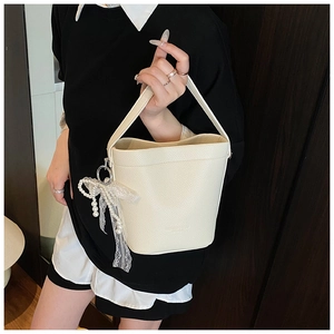 Detail of white lychee leather bucket bag with pearl and lace floral charm accessory