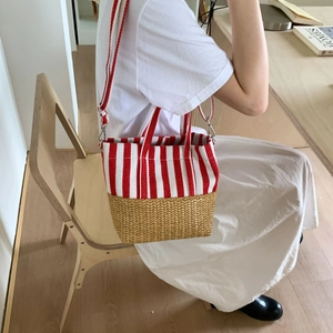 Detail of red and white striped tote bag with woven straw base and adjustable strap