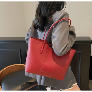 Détail du cabas en cuir rouge avec texture grainée et longues anses pour le quotidien