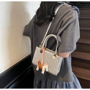 Détail du sac à main tissé argenté avec charm pégase rose et fine bandoulière élégante