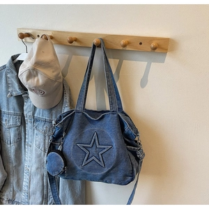 Detail of blue denim tote bag featuring embossed star design and circular coin purse pendant