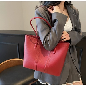 Vue rapprochée d'un grand cabas rouge vif avec texture en cuir grainé porté par un mannequin