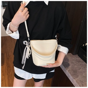 Detail of off-white lychee pattern bucket bag with lace bow and pearl pendant charm