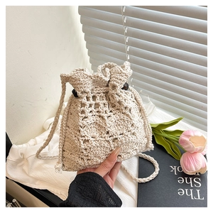 Détail d'un sac seau en crochet beige avec motifs ajourés et fermeture à cordon