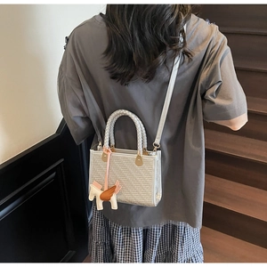 Détail du sac à main tissé argenté avec une breloque décorative en forme de pégase