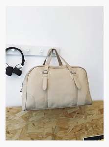 Close-up of beige canvas travel tote bag with decorative metal buckle in a home setting