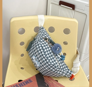 Détail du sac bandoulière pied-de-poule avec patch STAY et breloque en peluche
