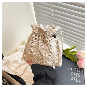 Détail du sac seau au crochet beige avec motif floral évidé et cordon en perles de bois