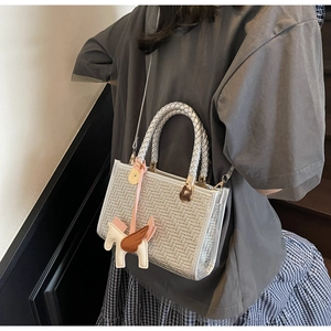 Détail du sac cabas tressé argenté avec breloque pégase et fine bandoulière amovible