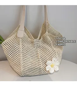 Detail of a beige knit tote bag featuring a 3D floral accent and leather shoulder straps