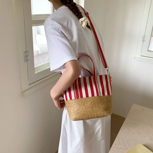 Detail view of canvas striped tote with straw base and adjustable wide shoulder strap